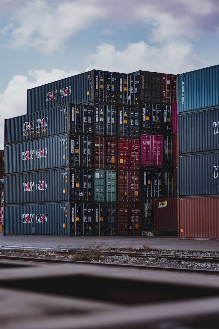Home High vertical stack of cargo containers at a port, symbolizing global logistics.