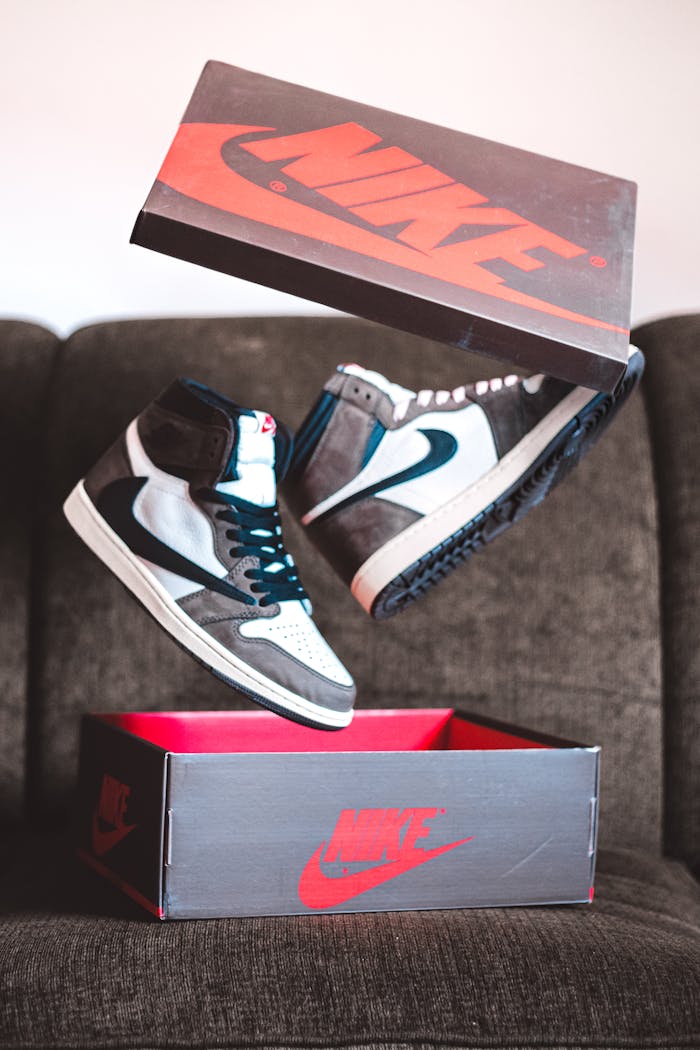 Stylish sneakers levitating above a Nike shoe box on a cozy couch, highlighting modern fashion.